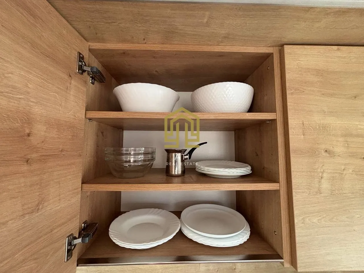 Open kitchen cabinet with shelves containing plates and bowls.
