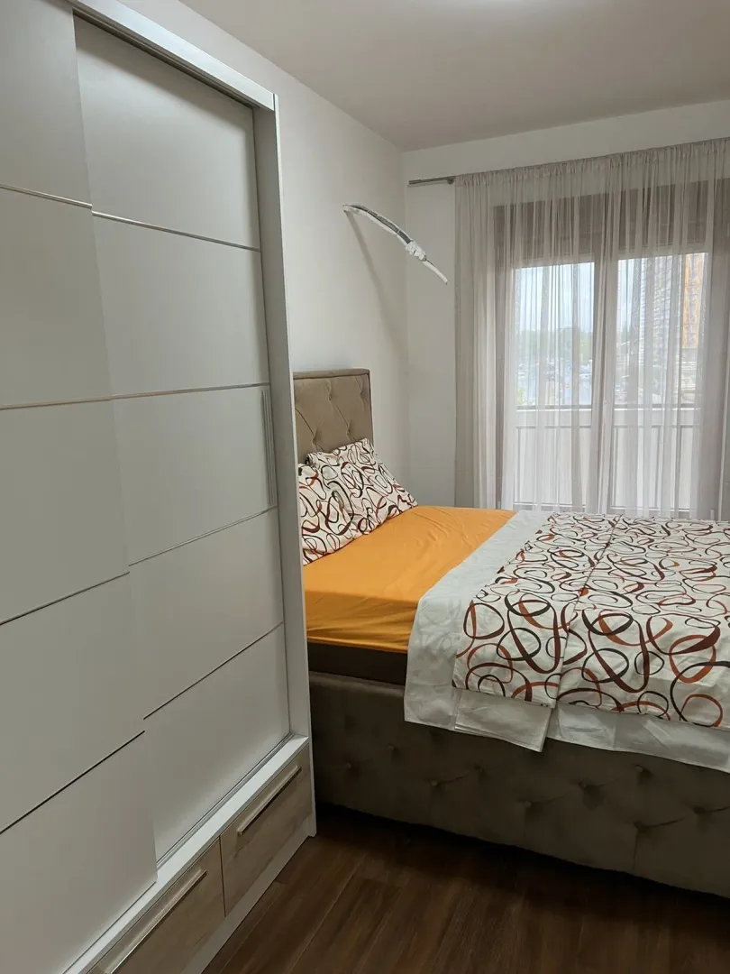 Svijetla spavaća soba sa bračnim krevetom i velikim bijelim plakarem.