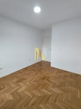 Prazna soba sa belim zidovima i drvenim parketom. - image 5