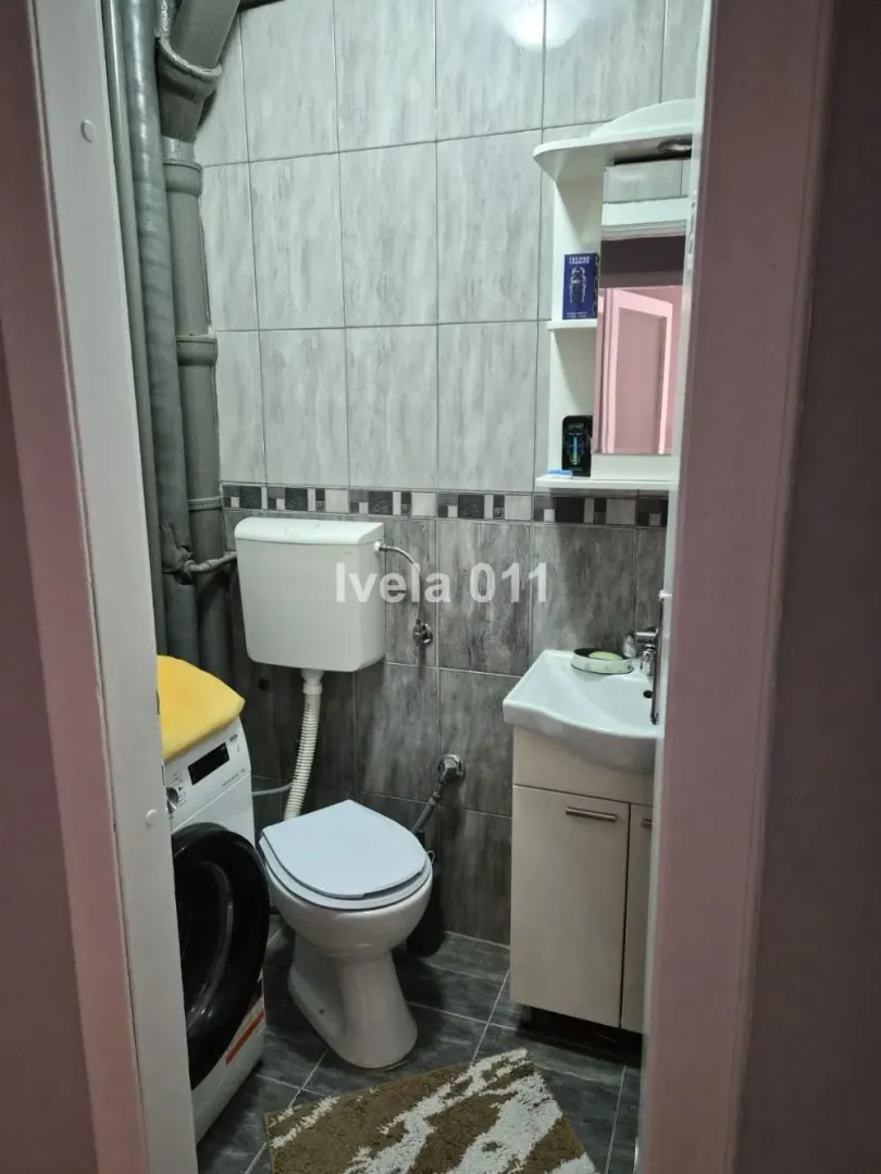 Manje kupatilo sa wc šoljom, umivaonikom i veš mašinom.