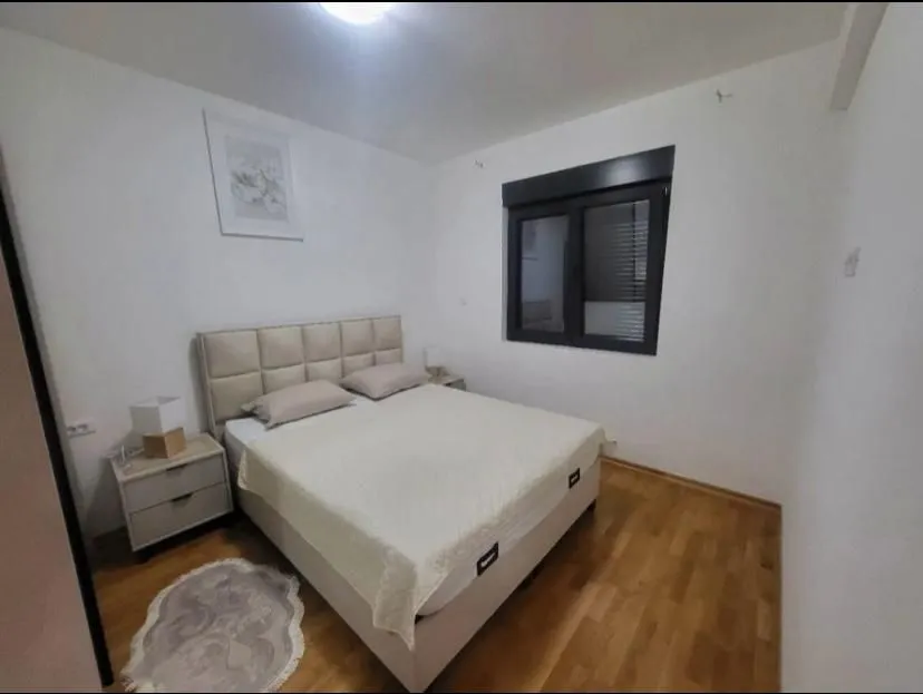 Bedroom with a large double bed, bedside tables and a window.