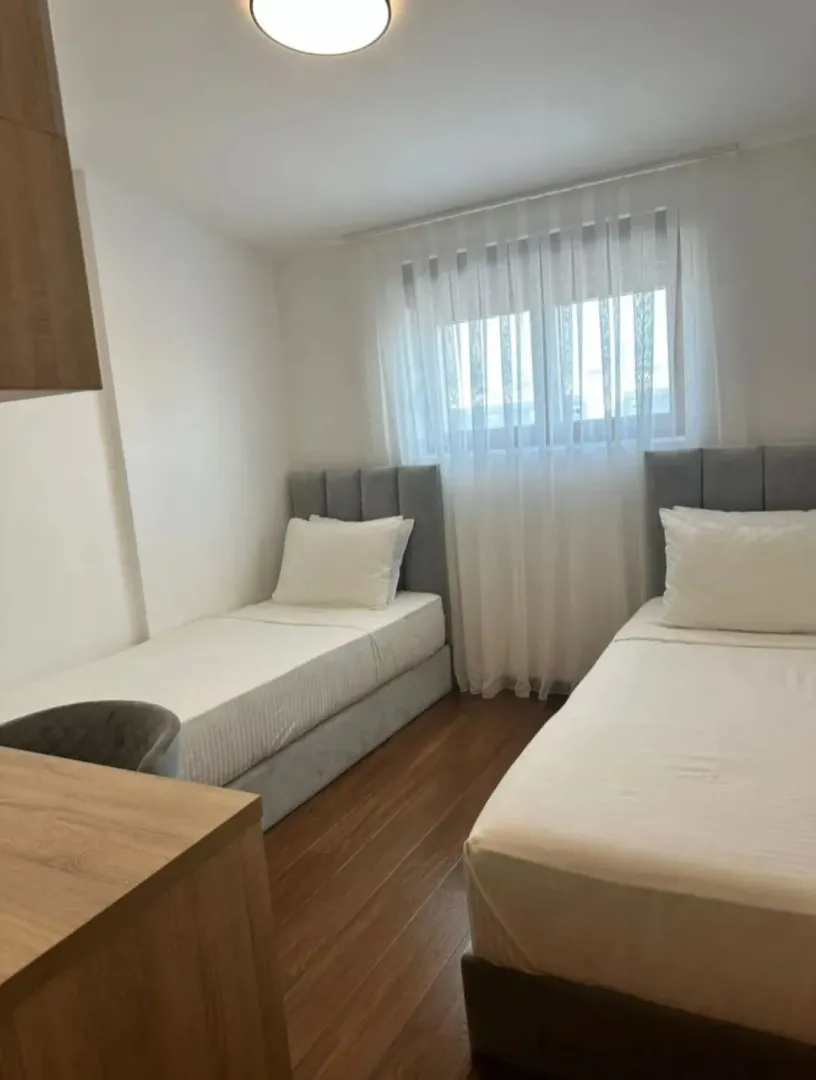 Furnished bedroom with two single beds and a desk.