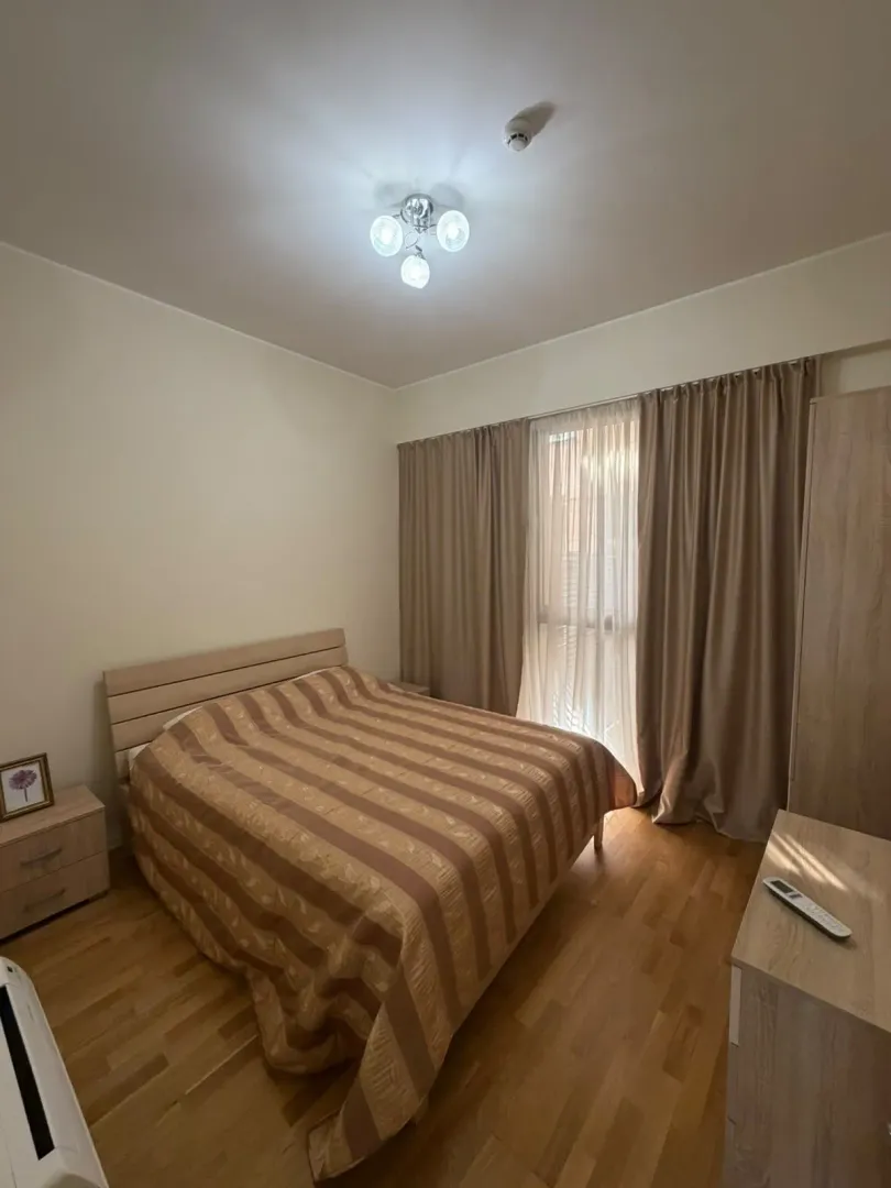 Furnished bedroom with a double bed, wardrobe, and a window with curtains.