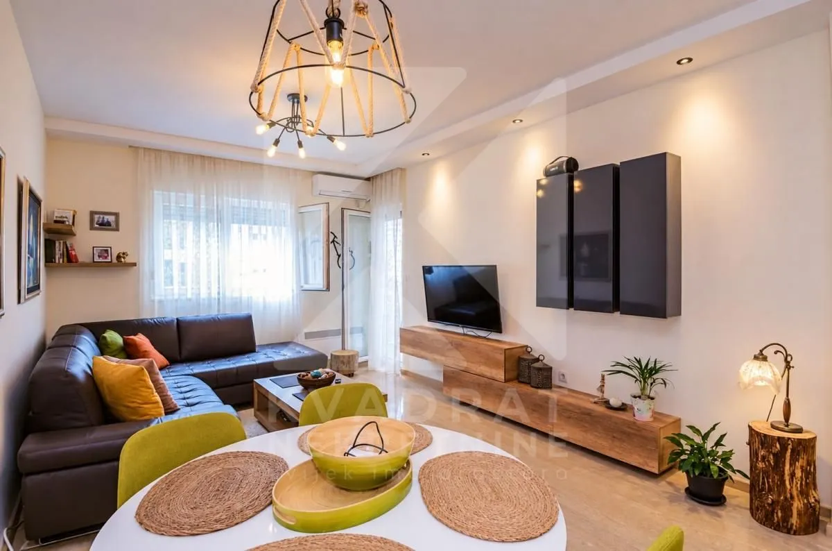 Living room with a sofa, TV unit, and a dining table in the foreground.