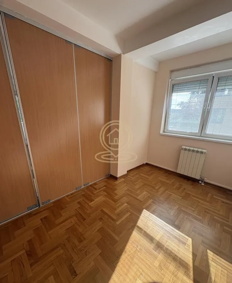Empty room with a built-in wardrobe and parquet flooring.