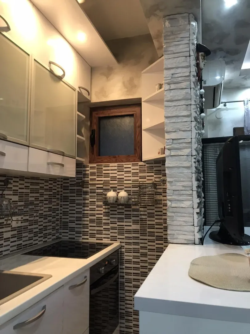 Kitchen with white cabinets, built-in appliances, and a decorative stone column.