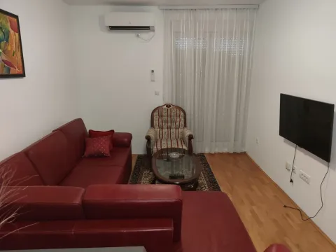 Living room with a red leather sofa and a wall-mounted TV. - image 9