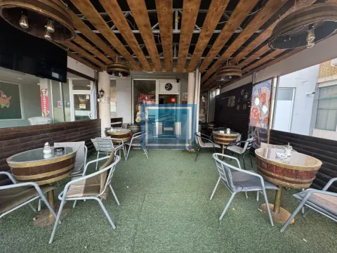 Covered terrace with tables and chairs furnished in a hospitality style. - image 10