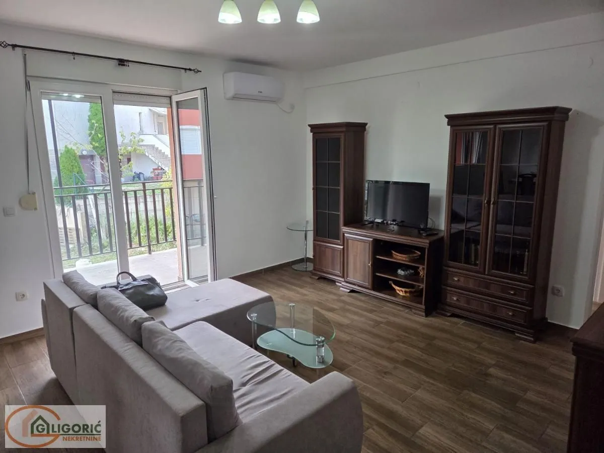 Living room with a sofa, wooden cabinet, and access to the terrace.