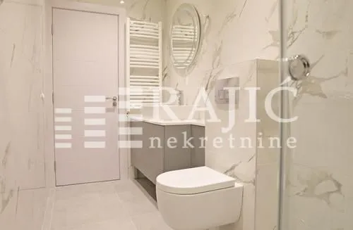 Modern bathroom with light marble tiles and sanitary ware.