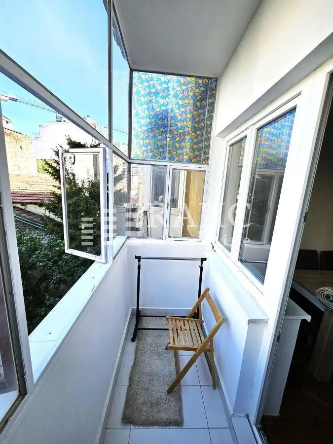Enclosed balcony with white frames and a chair.