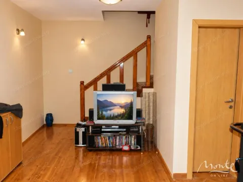 Living room with a television and wooden stairs. - image 13