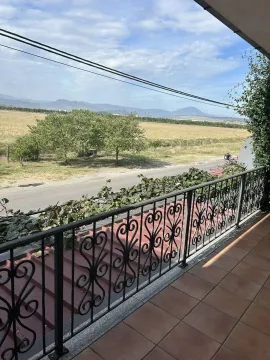 Balcony view overlooking a green field and distant mountains. - image 3