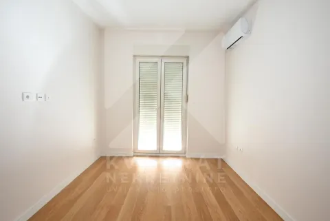 Empty room with wooden flooring, air conditioning unit, and balcony doors. - image 7