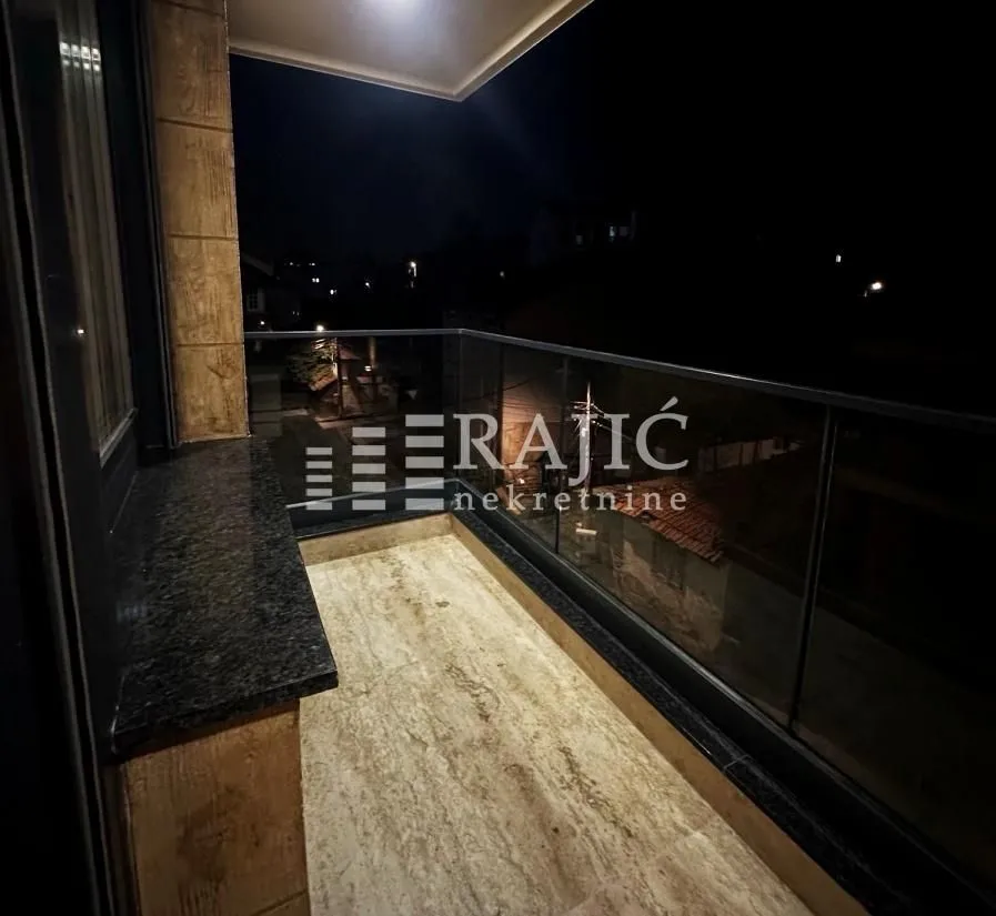 Lit terrace with a glass railing and a view at night.