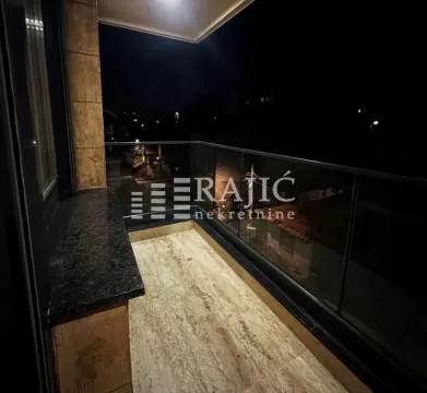 Lit terrace with a glass railing and a view at night. - image 8