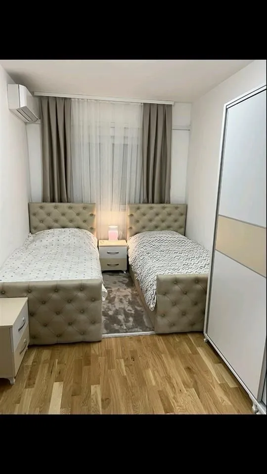 Svijetla spavaća soba sa dva singl kreveta i garderoberom.