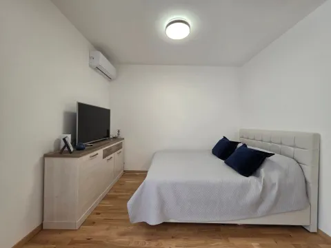 Spavaća soba sa bračnim krevetom, komodom i televizorom. - image 4