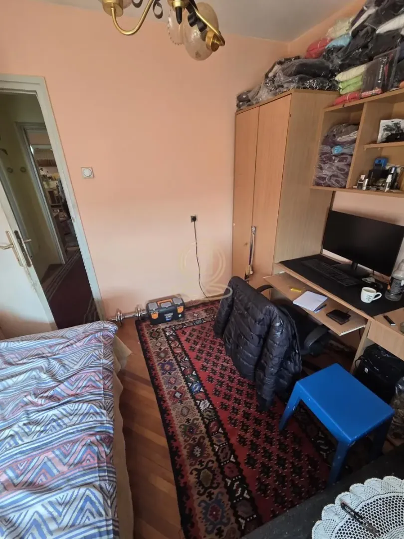 Nameštena spavaća soba sa radnim stolom i garderoberom.