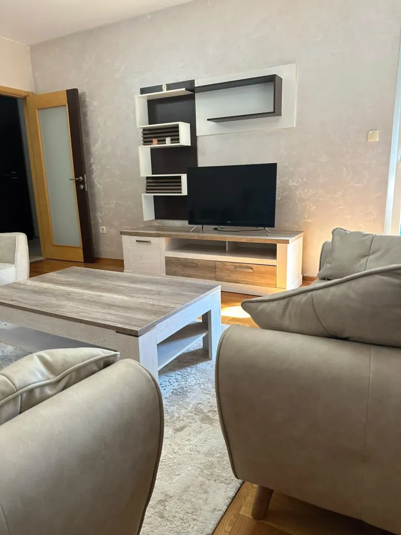 Dnevna soba sa garniturom, stočićem i TV komodom.