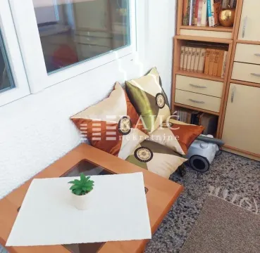 Part of the living room with a bookshelf, coffee table, and floor cushions. - image 10