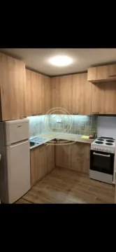 Small corner kitchen with wooden cabinets, refrigerator, and stove. - image 2
