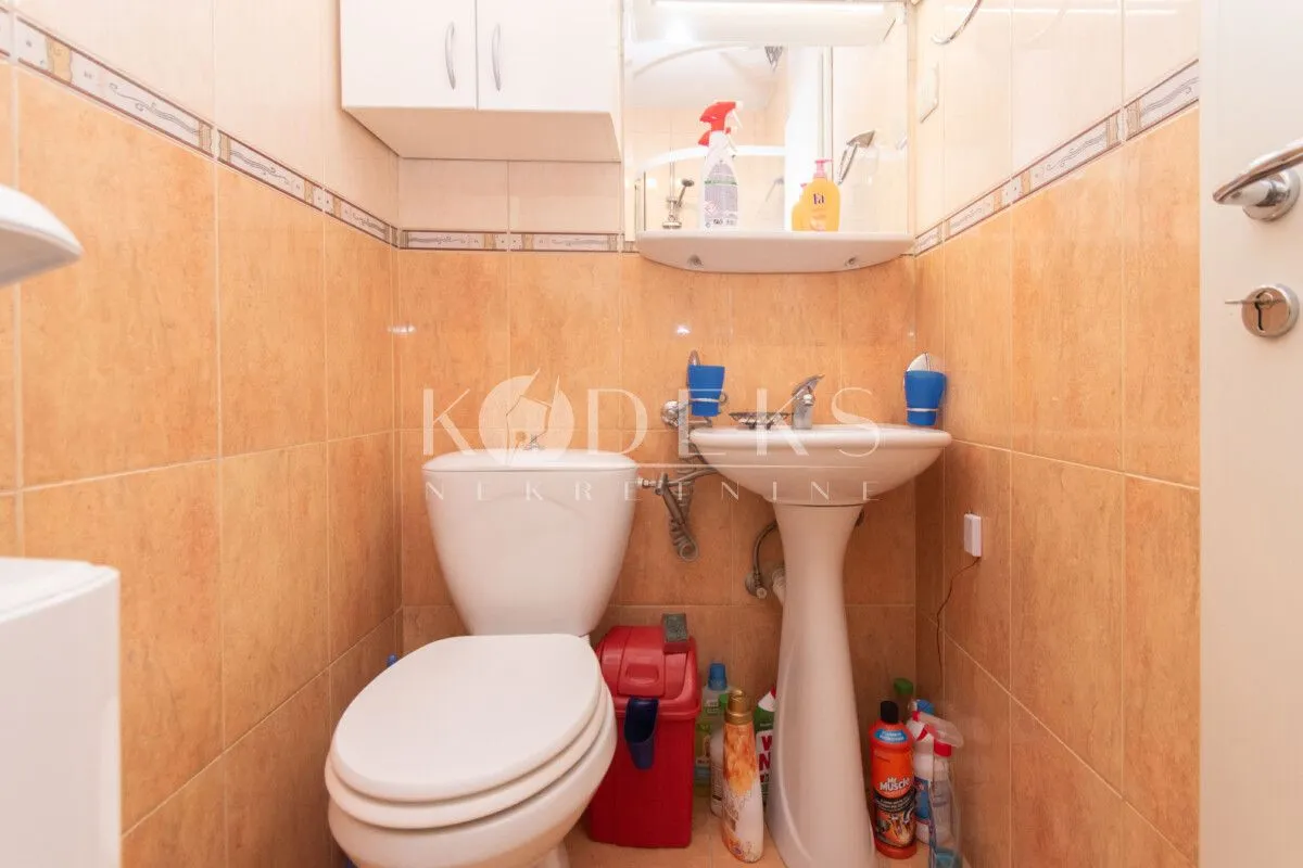Small bathroom with a toilet, sink, and wall tiles.
