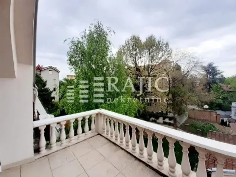 Spacious terrace with a stone railing and a view of greenery and surrounding buildings. - image 9