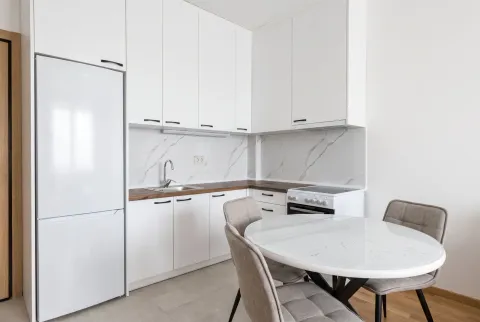 Modern white kitchen with a dining table and chairs. - image 3