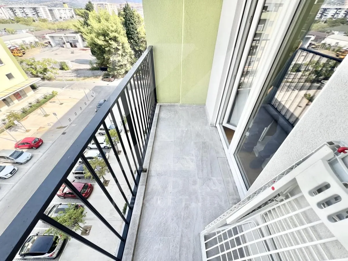 Covered balcony with a metal railing and a view of the neighborhood and parking lot.