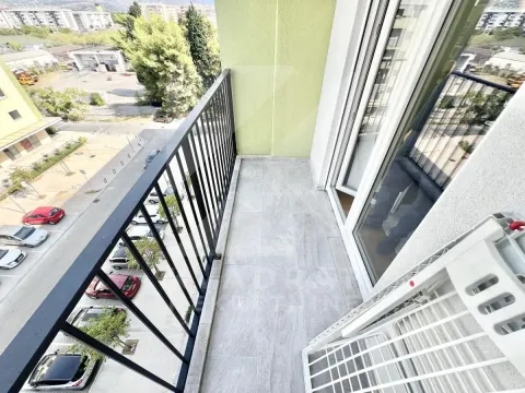 Covered balcony with a metal railing and a view of the neighborhood and parking lot. - image 11