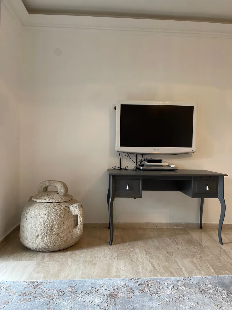 Living room with a wall-mounted TV, console table, and a traditional stone vessel.