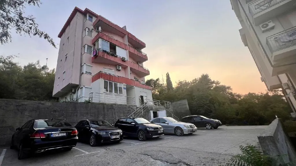 Exterior view of an apartment building with parking in front.