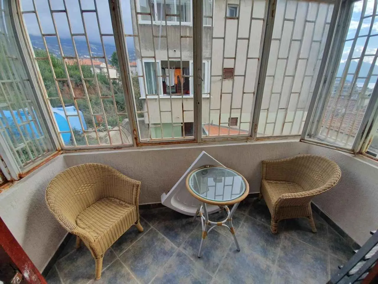 Zastakljeni balkon sa garniturom za sjedenje i pogledom na okolinu.