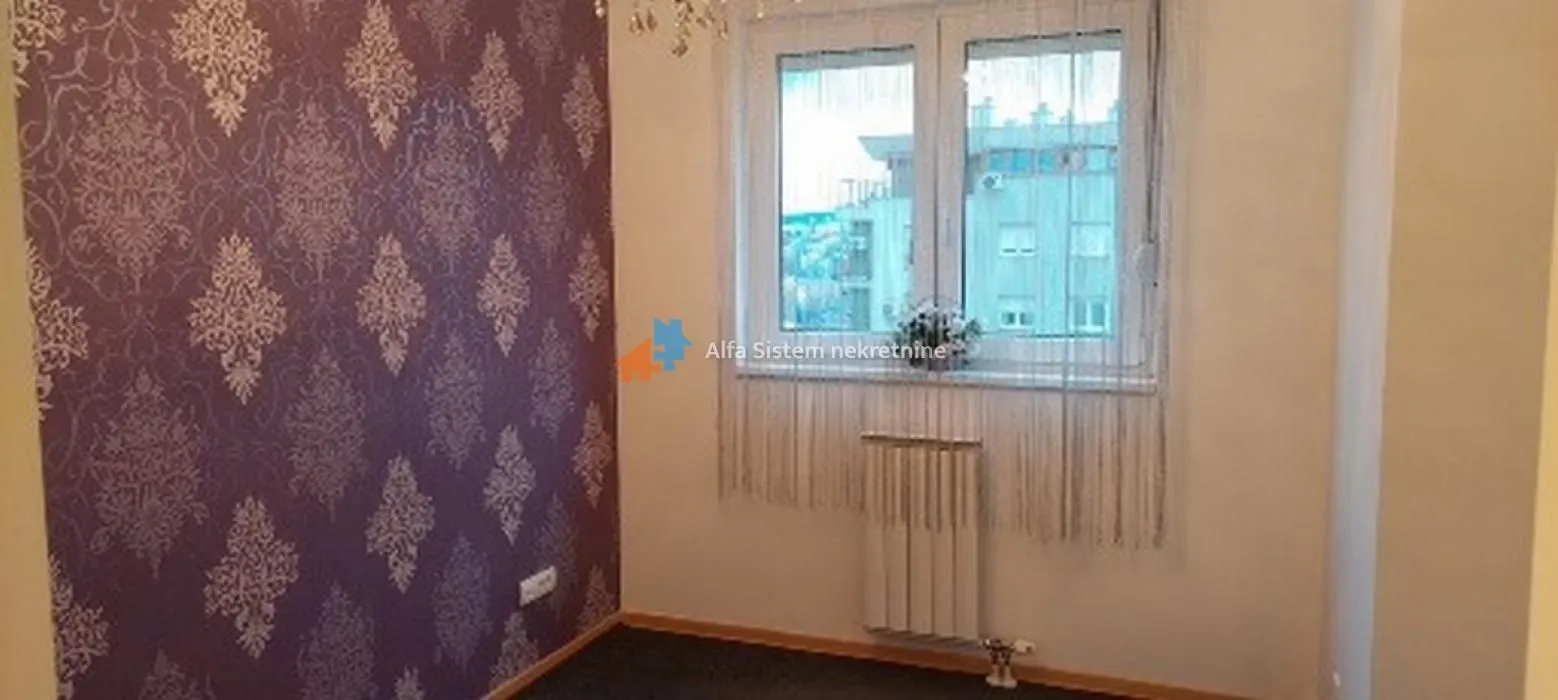 Manja soba sa tapetama na zidu i prozorom koji gleda na spoljašnjost.