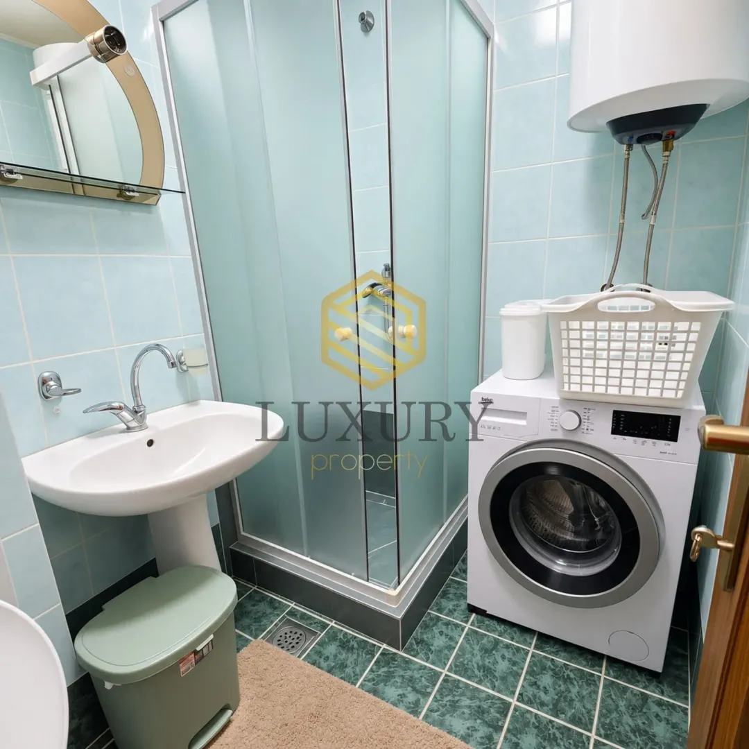 Smaller bathroom with a shower cabin, sink, and washing machine.
