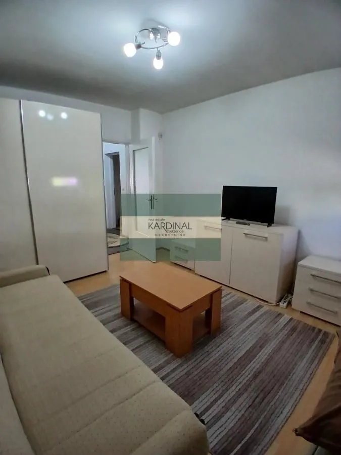 Dnevna soba sa garniturom, TV komodom i drvenim stočićem.