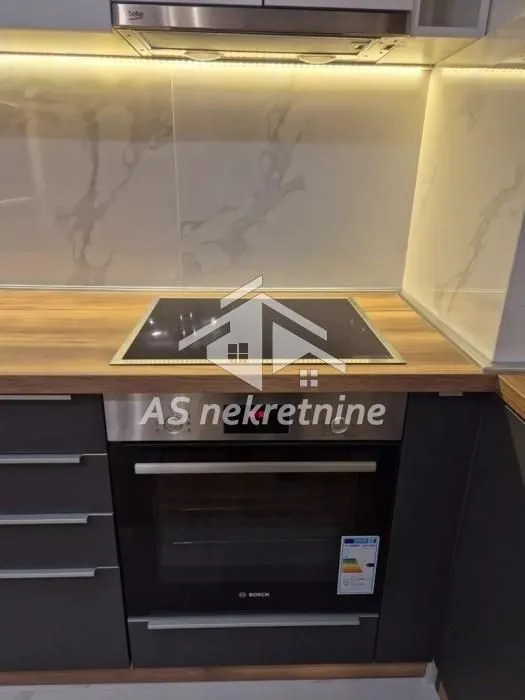 Modern kitchen with a built-in oven, induction cooktop, and extractor hood.