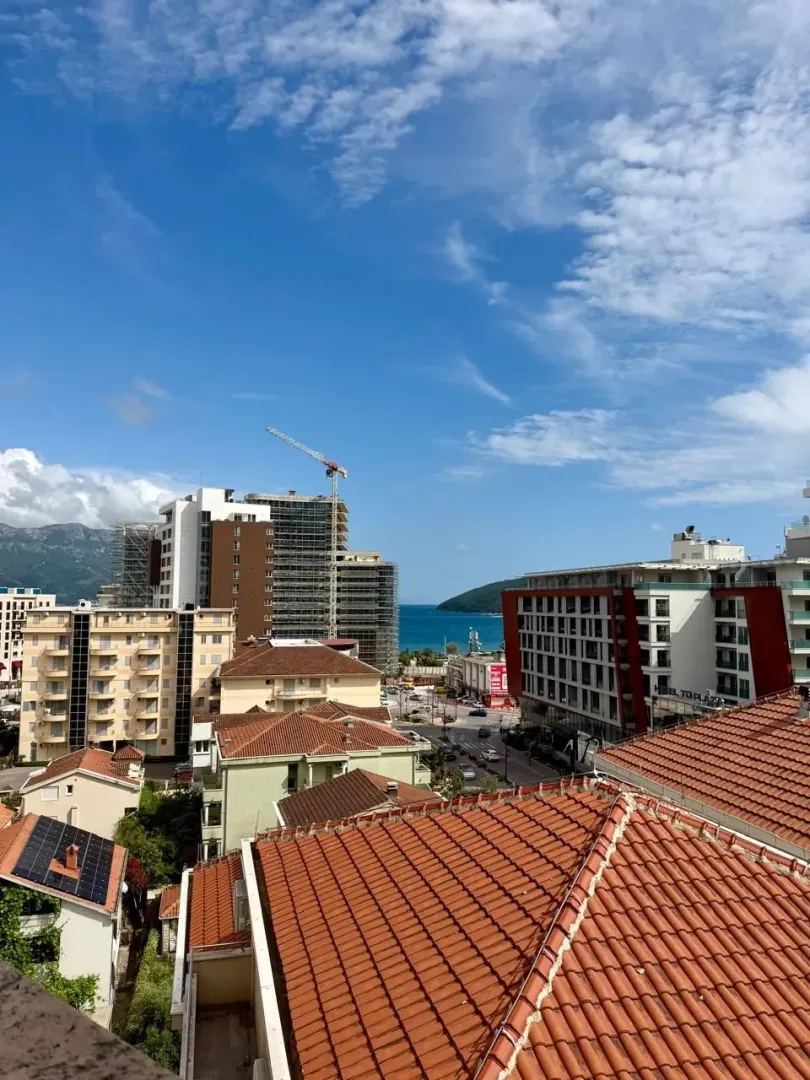 View from the terrace overlooking the city, rooftops, and the sea in the distance.