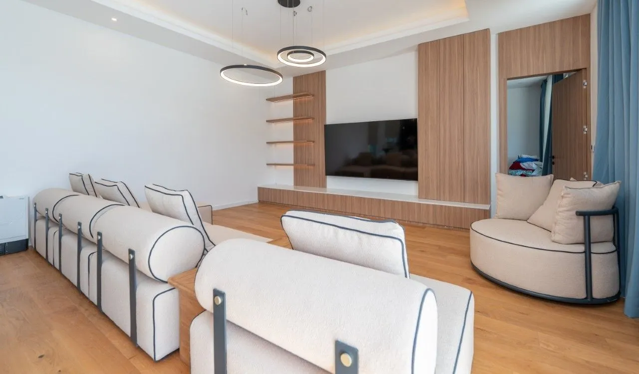 Living room with a sofa set, TV panel, and modern lighting.