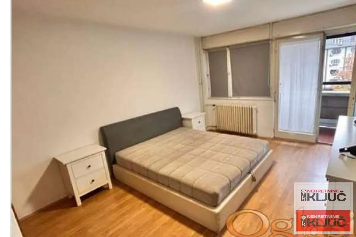 Spavaća soba sa bračnim krevetom i noćnim stočićima.
