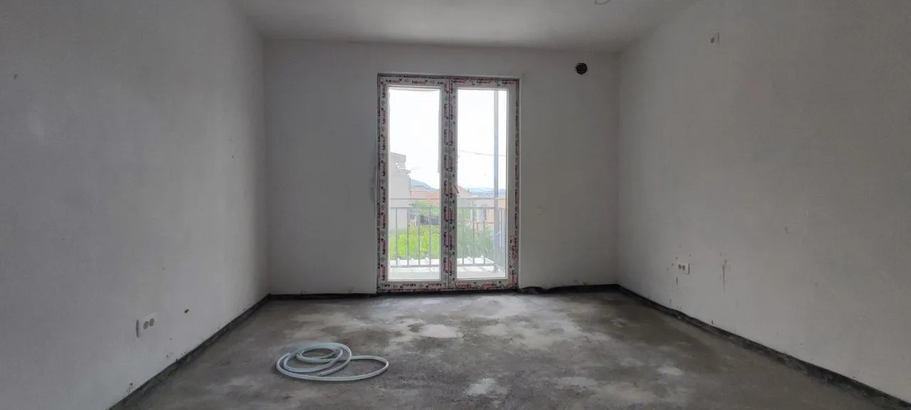 Empty room under construction with balcony doors and bare walls.