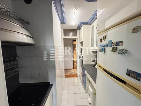 Small narrow kitchen with white cabinets and a stove. - image 5