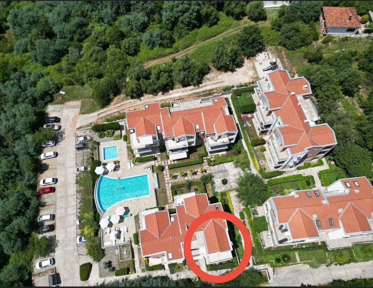 Pogled iz vazduha na stambeni kompleks sa bazenom i parkingom.