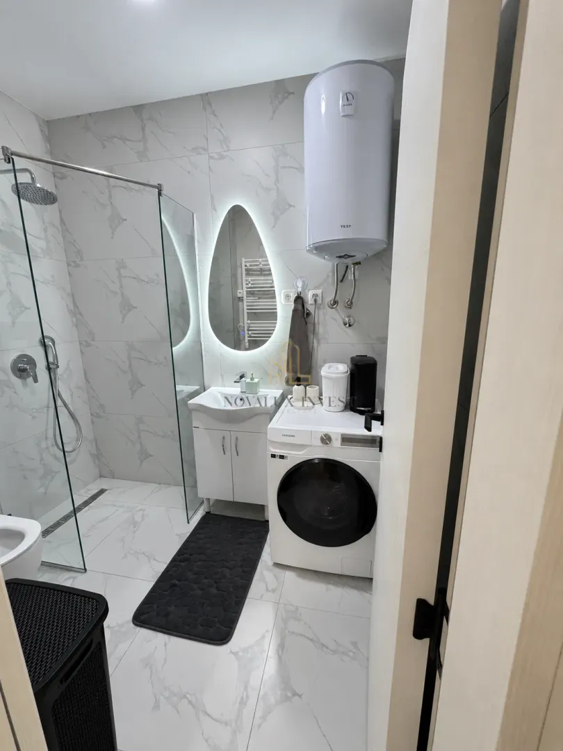 Moderne kupatilo sa tuš kabinom, umivaonikom i veš mašinom.