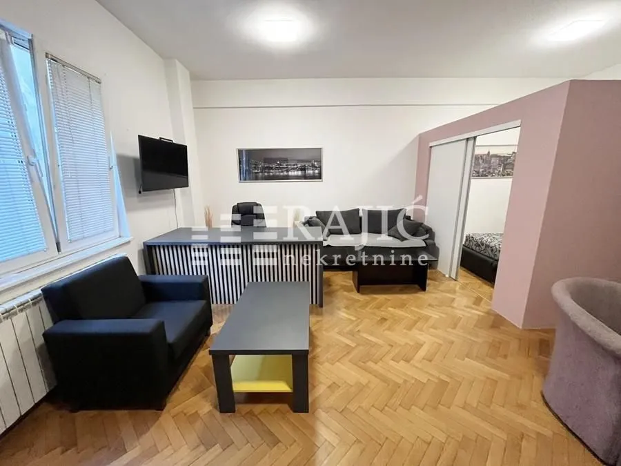 Living room with furniture, a desk, and parquet flooring.