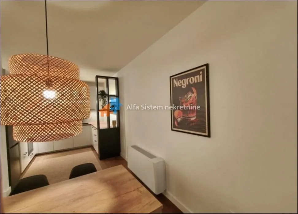 View of the dining area with a wooden table and the kitchen in the background.