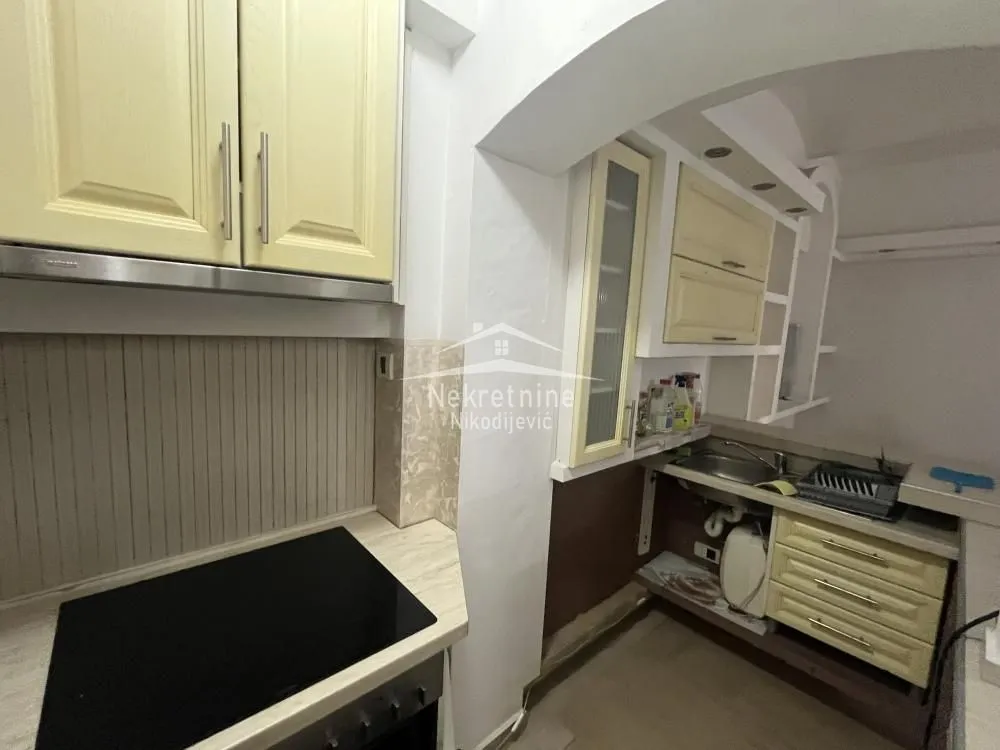 Small kitchen with light-colored cabinets and a built-in cooktop.