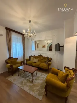 Dnevna soba opremljena garniturom u žutoj boji, stočićem i lusterom. - image 9