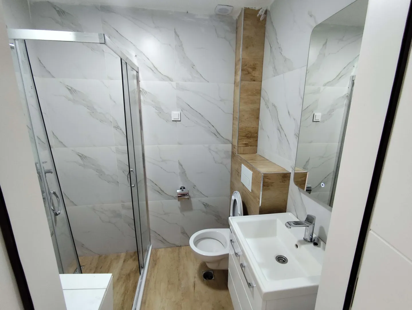 A modern bathroom equipped with a shower cabin, washbasin, and toilet.